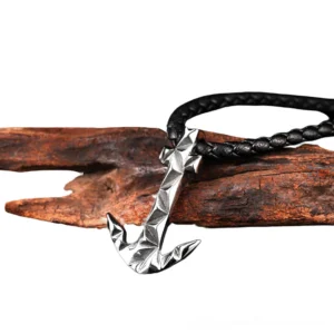 Anchor pendant necklace displayed on driftwood, oblique side angle showing silver-toned metal charm with woven black rope chain, alternative gothic jewelry