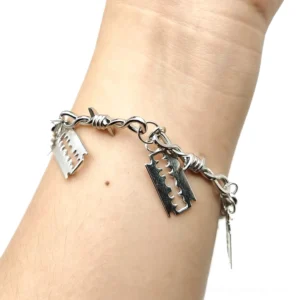 Barbed wire blade gothic bracelet worn on human wrist, silver metal chain with four sharp blade pendants, front view on white background