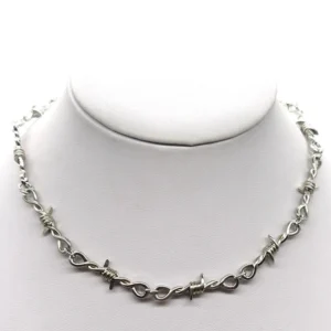 Barbed wire gothic choker necklace with thorn-pattern chain worn on mannequin neck, silver metal close-up front view