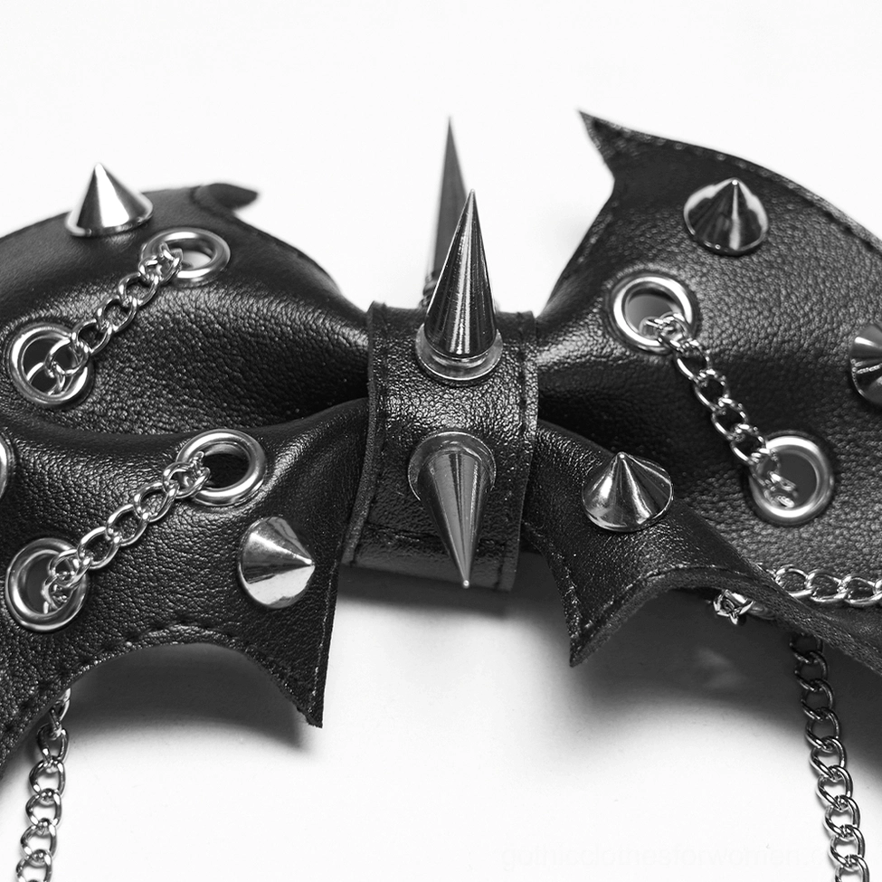 Macro close-up of bat wing clip highlighting silver spikes, rivets, and linked chain details