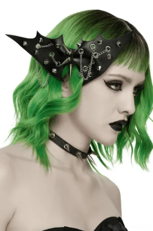 Black bat wing hair clip with silver spikes and chains, worn by model with green hair, shown in right profile view