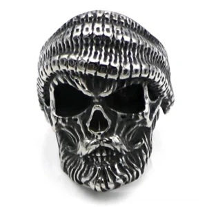 Frontal close-up of bearded skull ring displaying aggressive facial features and hand-knitted hat texture in antique silver