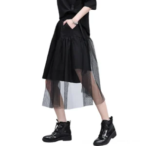 Black asymmetrical mesh gothic shorts showing three-quarter side profile with hand in pocket and elastic waistband detail