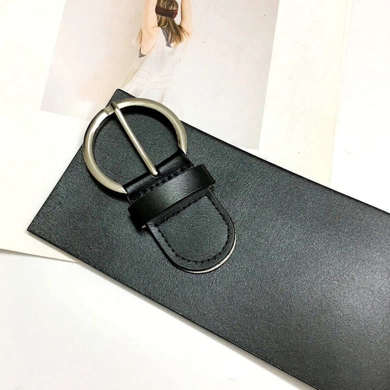 Black leather waist belt close-up oblique view showing smooth texture and polished metal buckle hardware