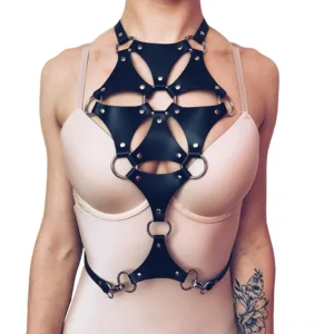 Front close-up view of black geometric PU leather chest harness with hexagonal cutouts and metal D-ring hardware on tattooed model