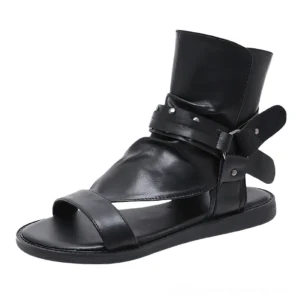 Single black gladiator sandal side profile displaying velcro buckle strap with industrial rivets and smooth leather construction