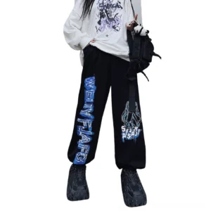 Black gothic wide leg anime print jogger pants styled with chunky sneakers and crossbody bag, full body front view