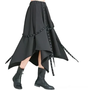 Asymmetrical black gothic midi skirt with grommet straps and irregular hemline, worn with black ankle boots on model