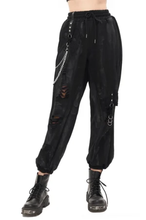 Black distressed gothic cargo pants with metal chains and rivets worn on female model, side low angle view