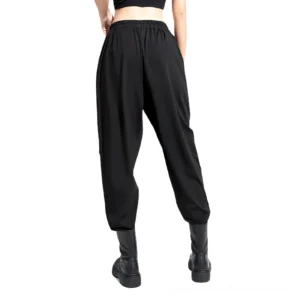 Rear perspective of black gothic high-waist trousers showing elastic waistband and tapered ankle cuffs with side ribbon detailing