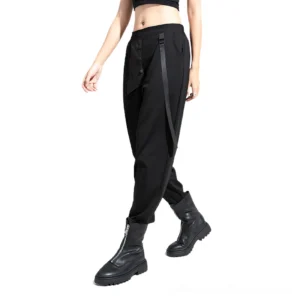 Black gothic harem trousers with side ribbon trim and asymmetric pockets worn by model in front three-quarter view with combat boots and cropped top