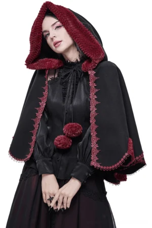 Black hooded gothic cape with wine red pompoms worn by model, front view with floral lace trim and fuzzy hood detailing