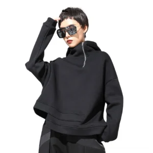 Black asymmetrical cropped gothic hoodie with half-zip closure, drop shoulders, and layered hem - front three-quarter view on model