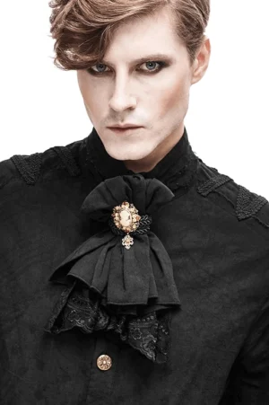 Men's black gothic lace jabot tie with cameo brooch, front upper body view worn on male model with white shirt background