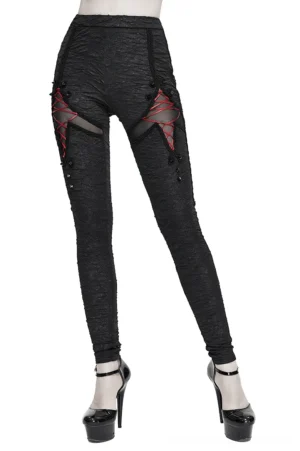 Black gothic lace-up leggings with red cross lacing and mesh cutouts worn by female model, front side view showcasing stud embellishments and elastic high waist