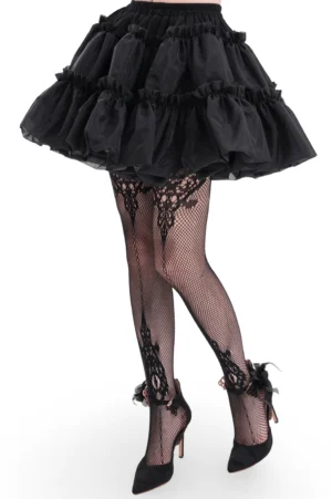 Black layered gothic lolita tulle skirt worn by model with fishnet stockings and platform heels, three-quarter side view showing multi-tier ruffled silhouette