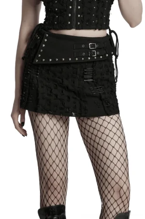 Black distressed gothic mini skirt with safety pins and studded waistband, side front view on model with fishnet stockings