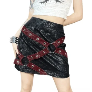 Black high-waisted gothic mini skirt with wine-red metal rivet harness straps, front three-quarter view on tattooed model