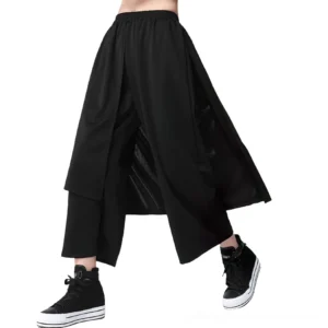 Black gothic wide-leg pants with asymmetrical layered overlay panel, front oblique view on model