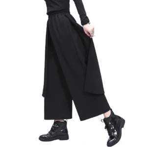 Black gothic high-waist wide-leg pants with asymmetric layered skirt overlay, side view on model showing cropped ankle length