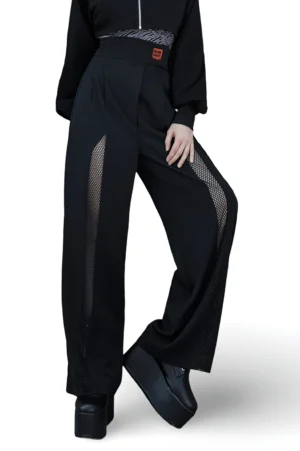 Black high-waisted wide leg gothic pants with removable shoulder strap and mesh panel accents, front three-quarter view on model