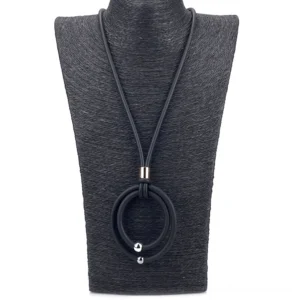 Close-up of black gothic pendant necklace on black jewelry bust displaying gold metal connector and round pendant details