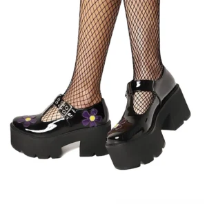 Black gothic platform Mary Jane pumps with purple flower appliqué worn with fishnet stockings, showing low side three-quarter view of chunky square heel and T-strap buckle