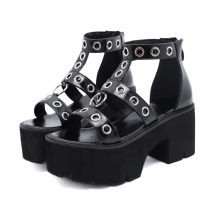 Black gothic platform sandals with rivet T-strap and metal eyelets, front view showing open toe design and chunky block heel