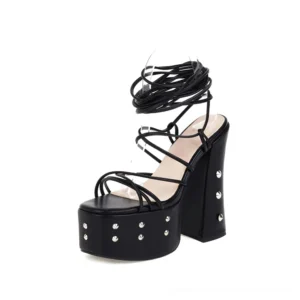 Black gothic platform lace-up sandals with studded square heel, three-quarter front view showcasing gladiator-inspired design and silver stud embellishments