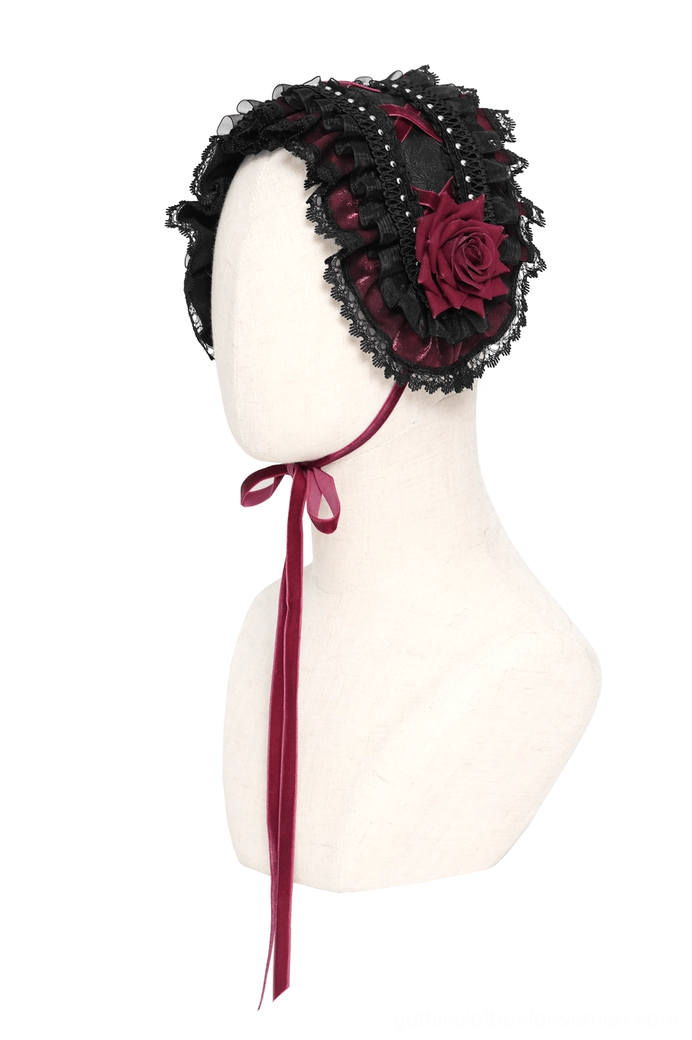 Side view of gothic bonnet on mannequin showing single wine-red rose and ribbon tie with structured shape