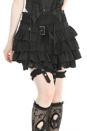 Black gothic layered ruffle mini skirt worn on model, left front side view showcasing ruffled hem and thigh garters with fishnet stockings