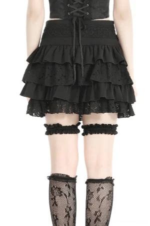 Rear view of black gothic mini skirt with layered ruffles and integrated thigh garters on model
