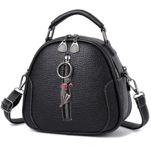 Black gothic shell crossbody bag with cat zipper pendant, front flat view showing litchi textured PU leather