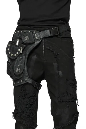 Black gothic harness waist bag with pyramid rivets and adjustable thigh strap worn on male model in ripped black pants, rear lateral view
