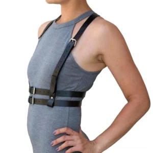 Women's black faux leather chest harness belt, side profile view demonstrating snug torso fit, metal buckle closure, alternative fashion harness