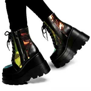 Black iridescent gothic platform ankle boots with holographic snake scale pattern, chunky lug sole, lace-up and side zipper closure, worn by model