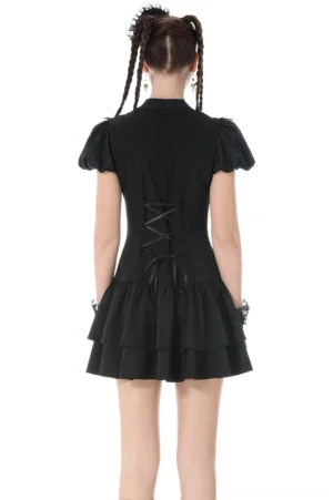 Black gothic puff sleeve dress back view displaying adjustable lace-up corset back closure, fitted waist, and cascading tiered ruffle hem with model wearing double braids
