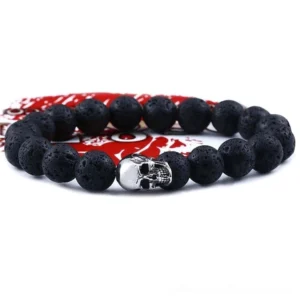 Black lava stone skull bracelet flat lay - 10mm beads with silver stainless steel skull charm on red fabric background