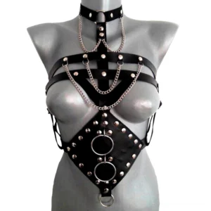 Black leather body harness for women front view with studded rivets, metal chains, and dual O-rings on gray mannequin