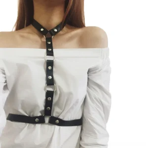 Black leather chest harness with integrated choker worn by model in close-up front view showing silver O-rings and rivets