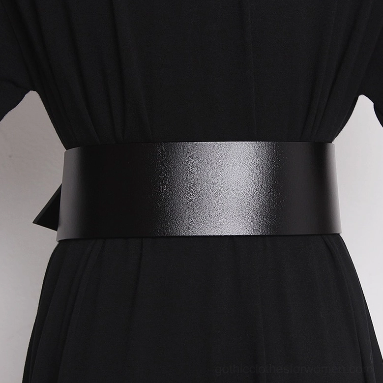 Black leather wide waist belt worn on female model in black dress showing matte texture and smooth finish