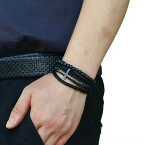 Adjustable black leather cross bracelet worn on male wrist, side view showing layered design and lace-up closure in casual daily wear setting