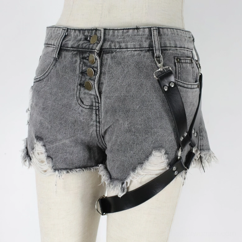 Black leather cross harness with silver rivets paired with grey button-fly frayed denim, side front view