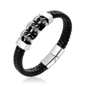 Black braided leather skull bracelet with three silver skull charms and stainless steel magnetic clasp, displayed on white background overhead view