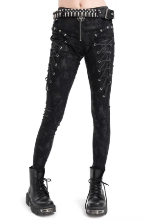 Black pentagram lace-up gothic skinny pants with skull studs worn by female model, front three-quarter view with studded belt and combat boots