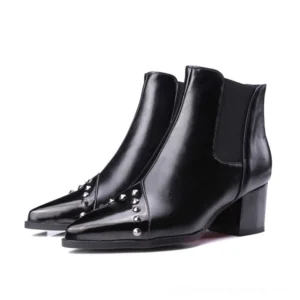 Black pointed studded Chelsea ankle boots with metal rivets, block heel, front-side view on white background