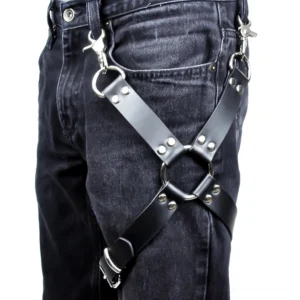 Black PU leather leg harness with cross straps and silver hardware worn over dark wash denim, front side view showing gothic bondage style