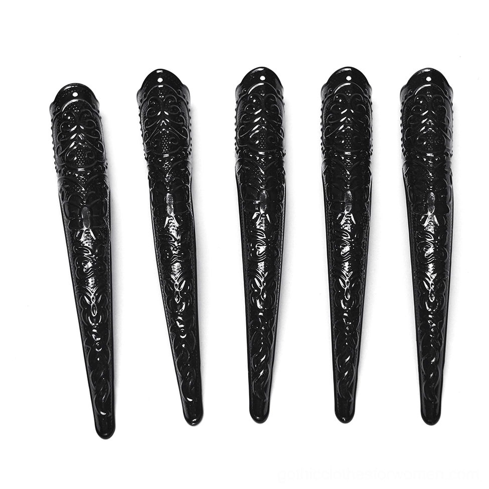 Five glossy black resin demon claw tips with embossed carved patterns, flat lay arrangement