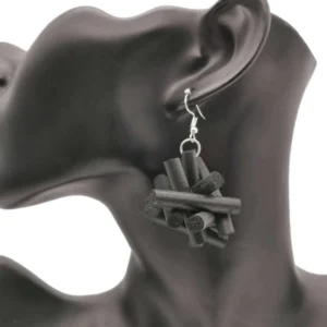 Black rubber drop earrings with crossed-stick design worn on mannequin ear model, side close-up studio photography