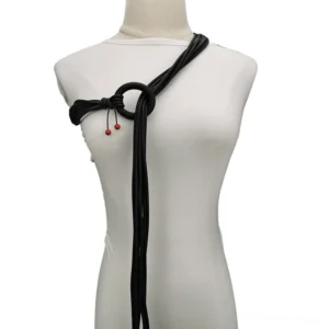 Black rubber gothic long necklace with red beads on white dress mannequin - front oblique view showing adjustable design and aluminum ring clasp